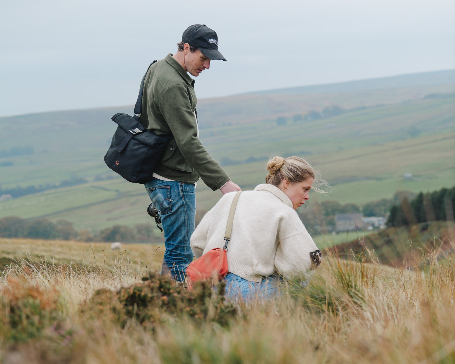 Two people walking through a field with a scenic background